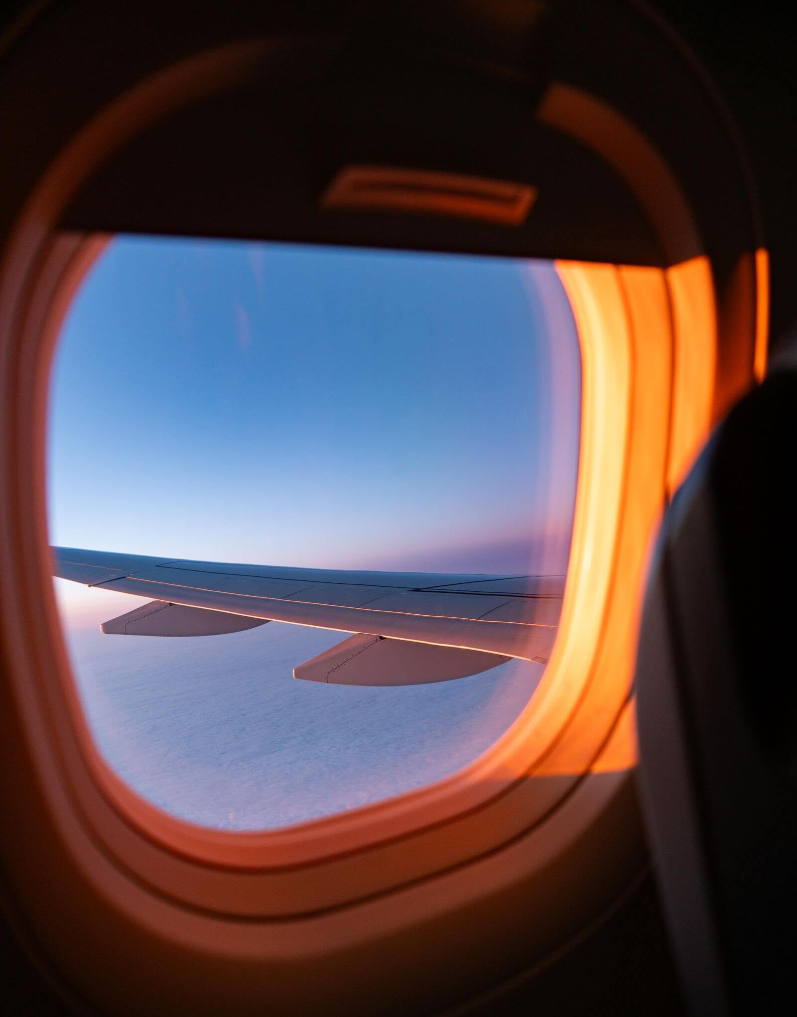 Airplane wing view through window at dusk