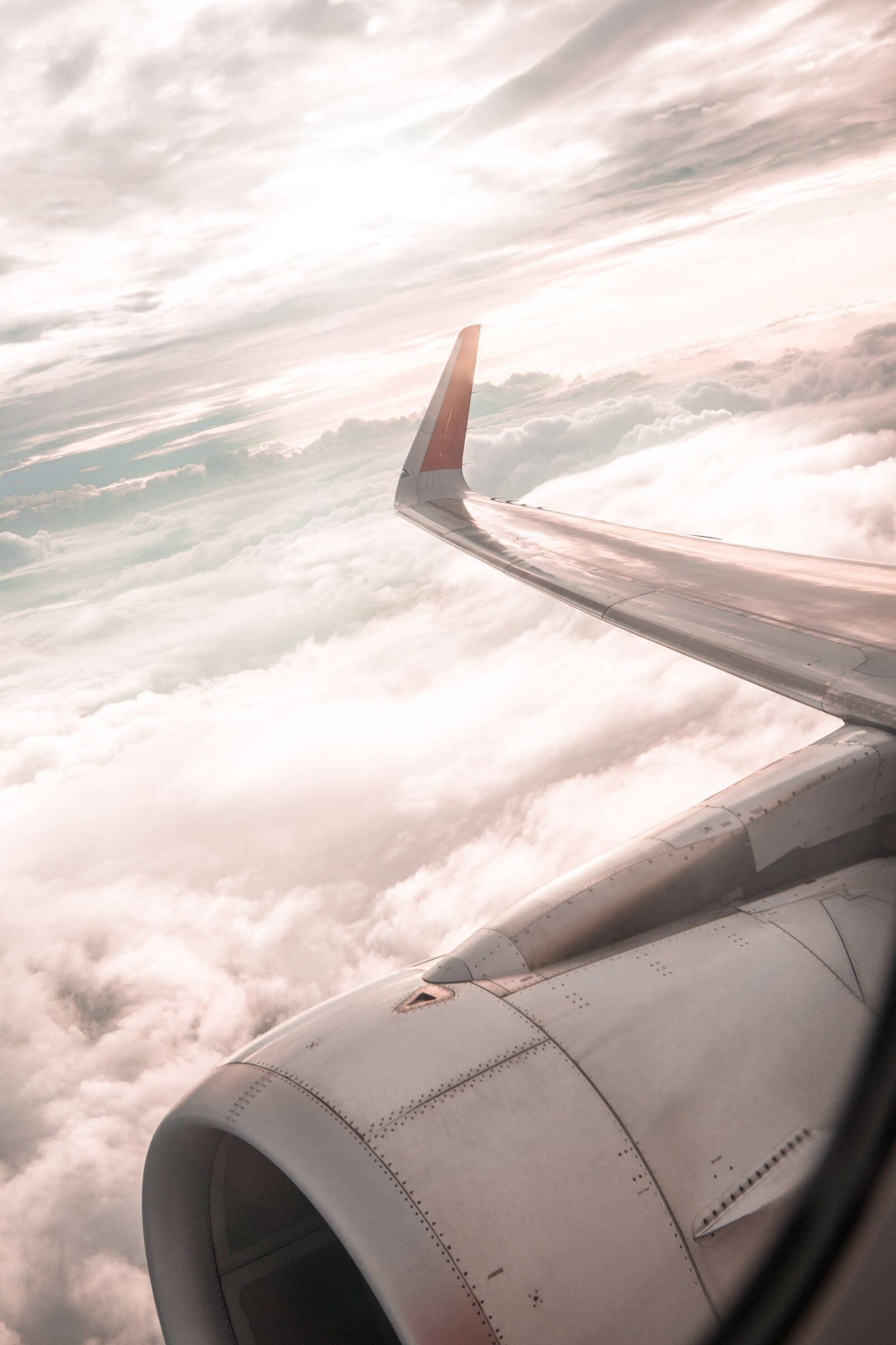 Airplane wing and engine above clouds at sunset