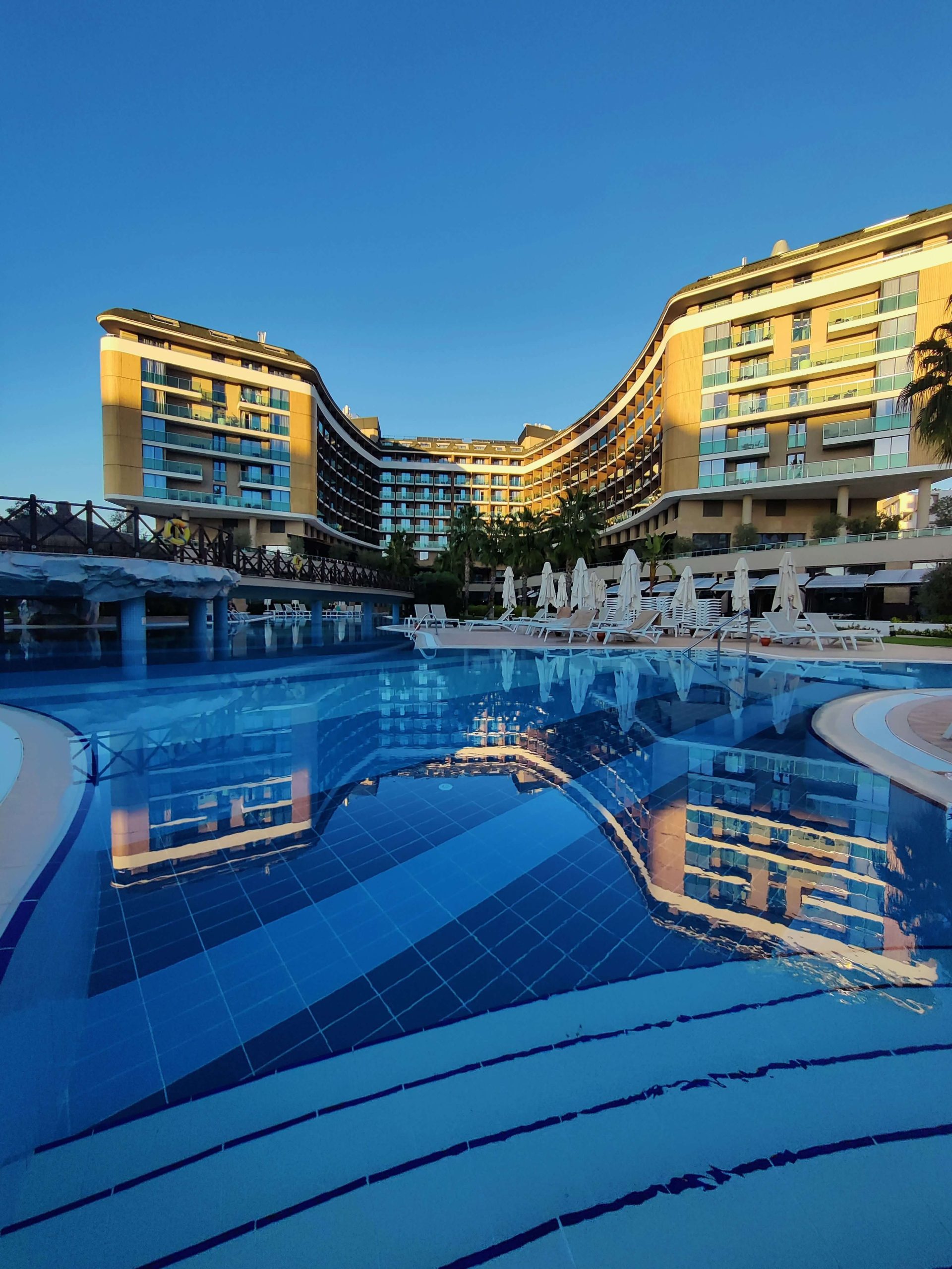 Hilton Honors American Express Card Review: Is a No-Fee Hilton Card Worth It? 3 Resort hotel pool at dusk, representing Hilton Honors card benefits