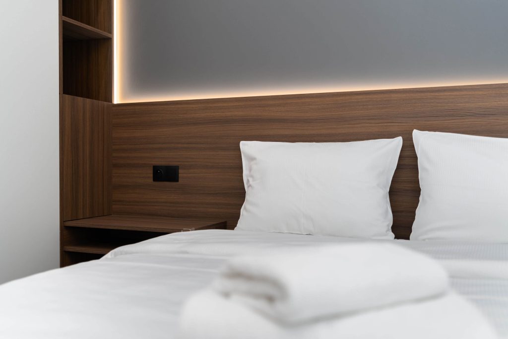 Modern luxury hotel room with wood headboard and white linens