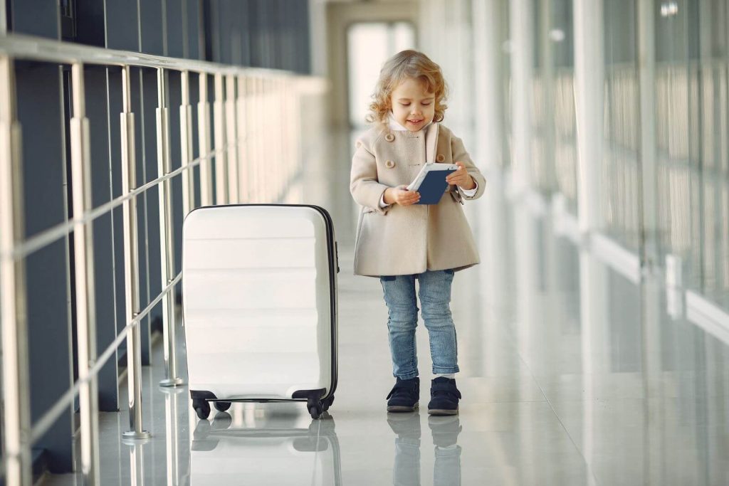 What Is the US Airlines Policy for Unaccompanied Children on International Flights? 2 Young child with suitcase and passport in an airport corridor